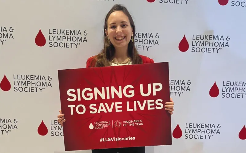 A photp of Elizabeth Foster ’15 holding a sign that reads