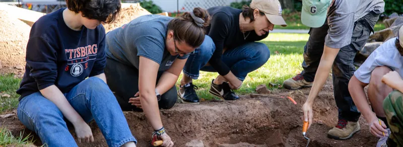 group of students and a prof at a dig