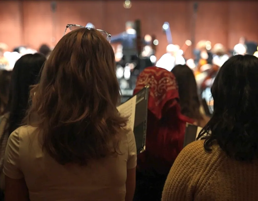 Students in audience sing before symphony on stage